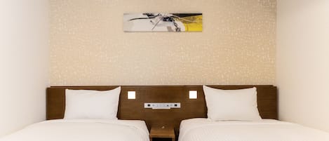 A hotel room with two beds, a wooden headboard, a small bedside table, and a wall-mounted artwork.
