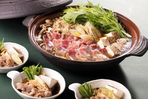 A hot pot with various ingredients like tofu, meat, mushrooms, and greens.