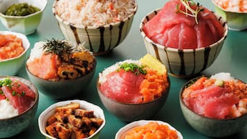 Variedad de platos, como sushi y arroz, servidos en recipientes pequeños.