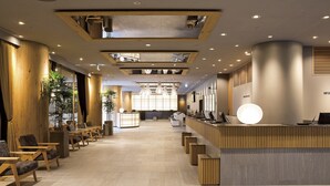 A modern reception area with a wooden reception desk, seating area, and large windows. - Shinjuku Washington Hotel Main (Tokyo)