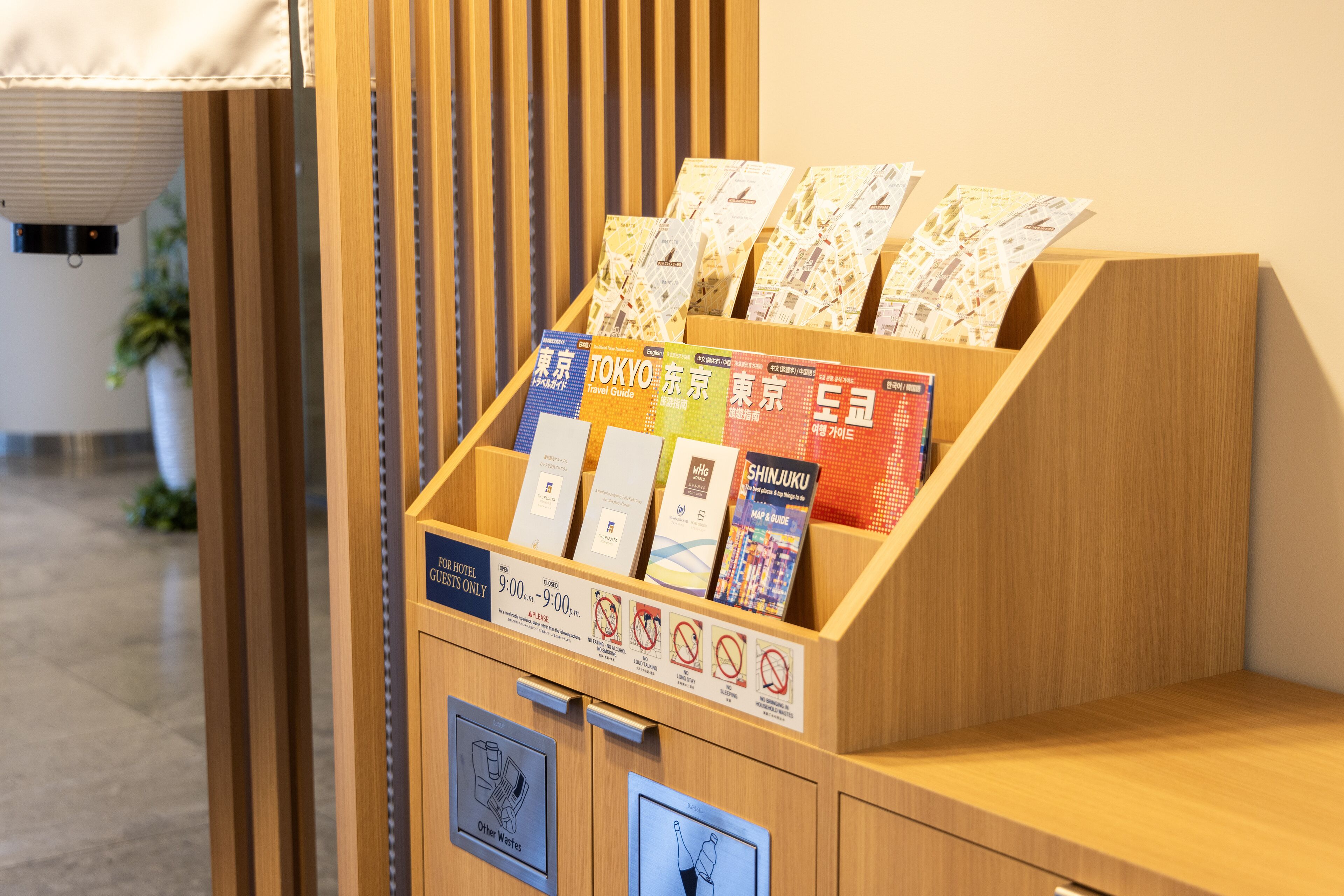 Een houten etalage met reisgidsen en een bord waarop de uren voor hotelgasten staan aangegeven.