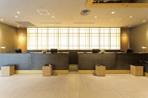 A reception area with a modern design, featuring a large window with vertical blinds, a reception desk, and a seating area.