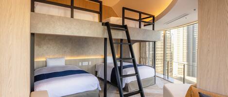 Ett modernt hotellrum med våningssängar, en stege, en soffa och ett stort fönster med utsikt över staden.