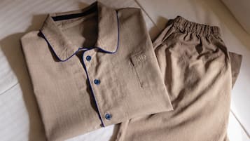 A neatly folded beige shirt with blue piping and buttons, and matching beige pants with a pocket and a label reading "WHG".