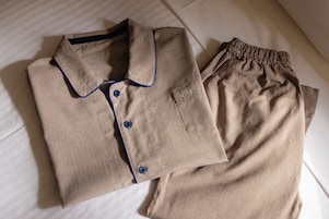 Una camisa beige impecablemente doblada, con ribetes y botones azules, y pantalones beige a juego con un bolsillo y una etiqueta que dice 