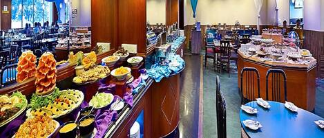 A buffet with various food items and a seating area with tables and chairs.