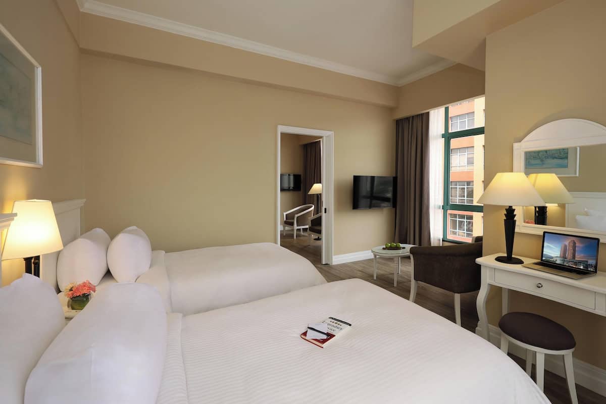 A hotel room with a large bed, a desk with a laptop, a chair, and a television.