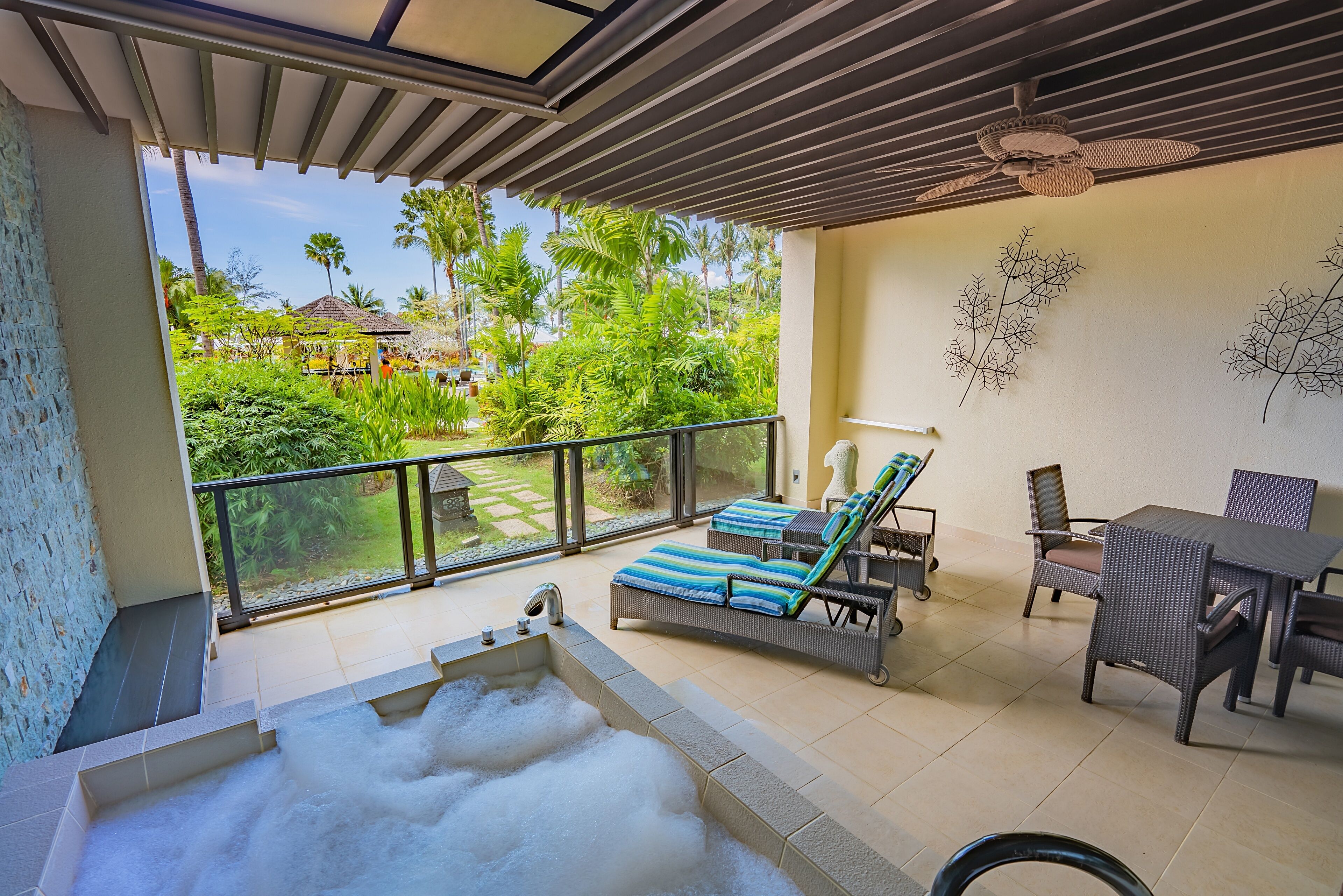 A balcony with a hot tub, lounge chairs, and a dining area with wicker furniture.