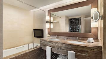 Un baño moderno con tocador de mármol, dos lavamanos, un espejo grande y una bañera.