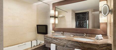 A modern bathroom with a marble vanity, two sinks, a large mirror, and a bathtub.