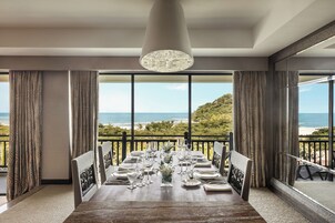 Un comedor con vistas al océano, ventanas amplias y una araña.