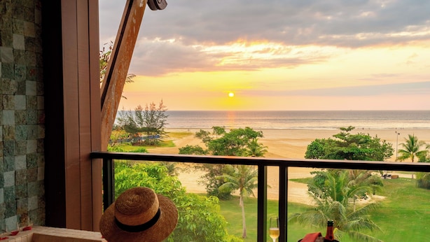 A person relaxing in a bathtub with a sunset view, a bottle of champagne, and rose petals on the floor. - Shangri-La Rasa Ria, Kota Kinabalu (Tuaran)