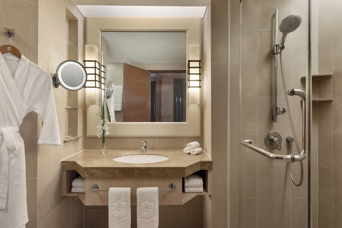A modern bathroom with a sink, mirror, towel rack, and shower.