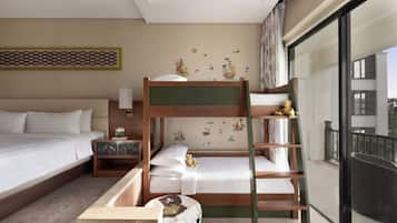 A hotel room with a bunk bed, a bedside table with a lamp, a decorative wall piece, and a large window.