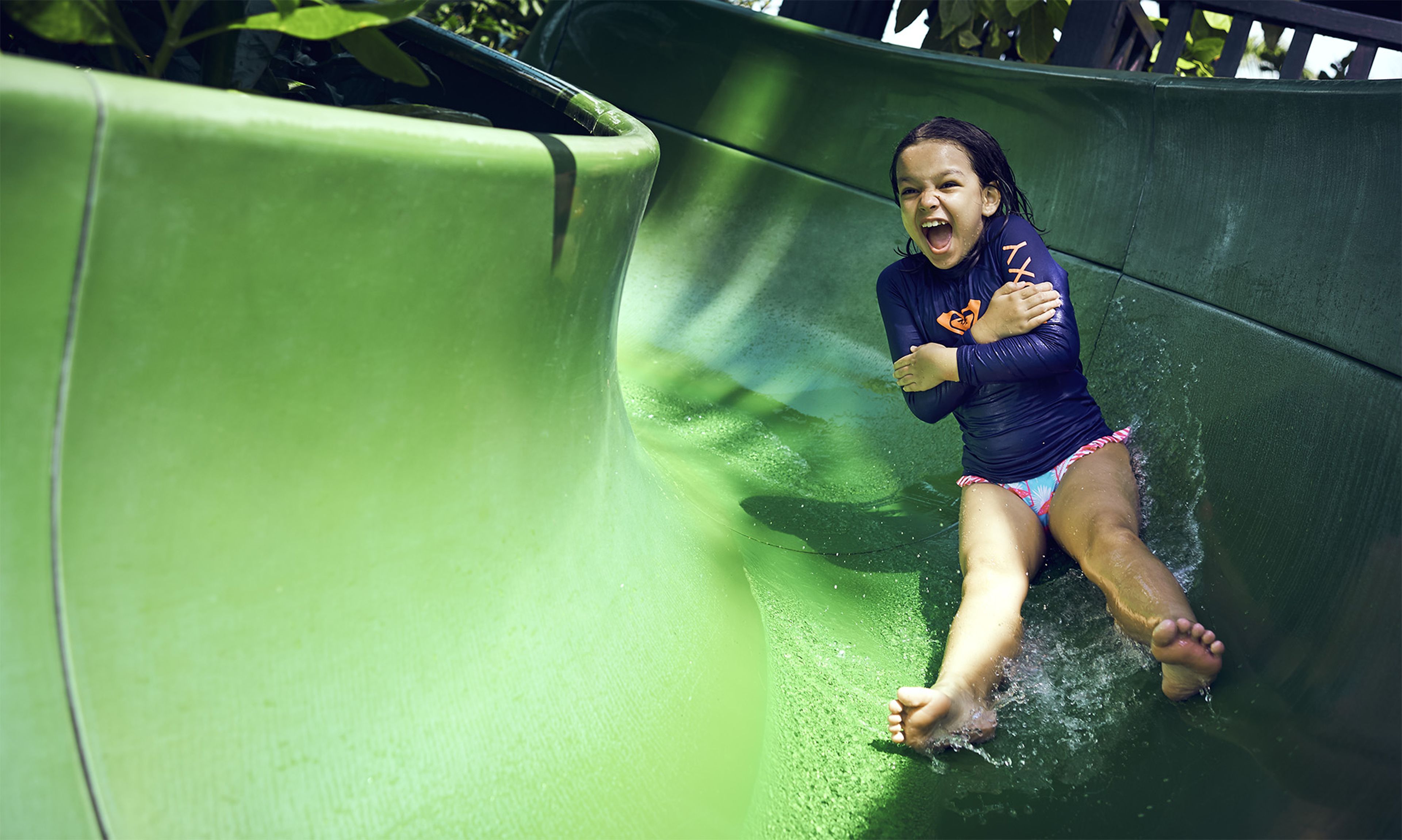 A child sliding down a green slide.