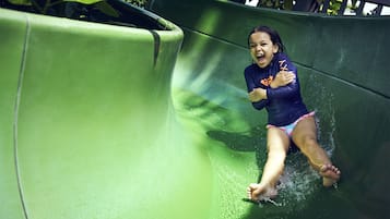 A child sliding down a green slide.