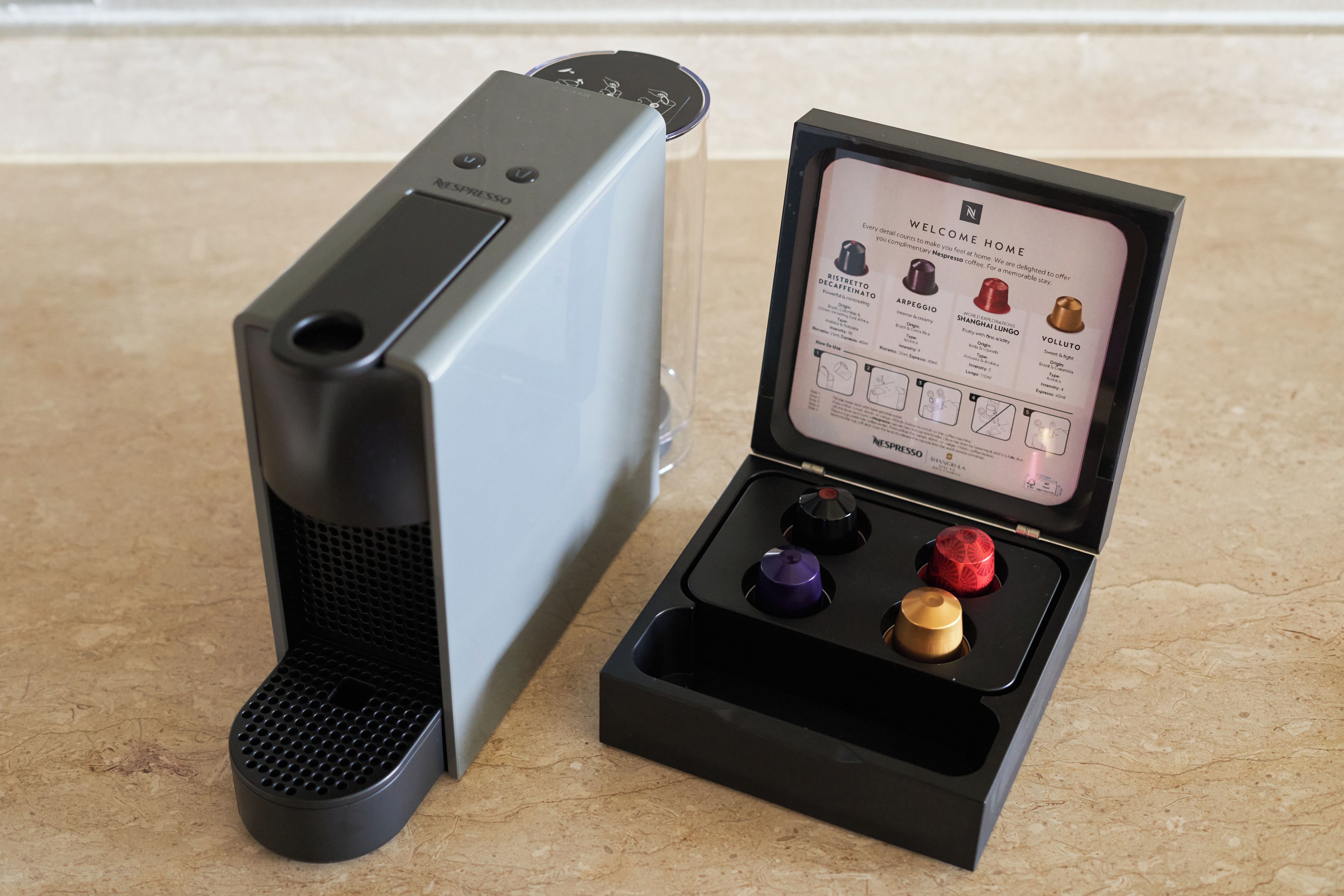 A Nespresso coffee machine with a manual and four coffee capsules.