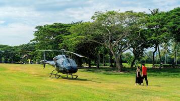 A helicopter parked on a grassy field with trees in the background.