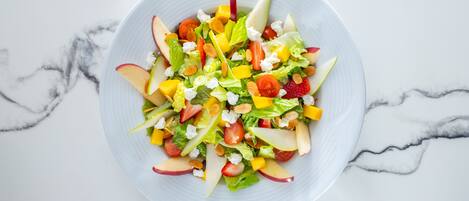Un tazón de ensalada de frutas sobre una superficie de mármol.