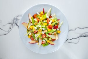 A bowl of fruit salad on a marble surface.