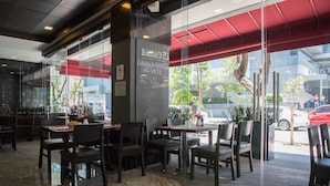 Un restaurante con mesas al aire libre, un menú en una pizarra y un toldo rojo.