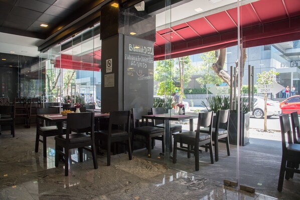 A restaurant with outdoor seating, a chalkboard menu, and a red awning.
