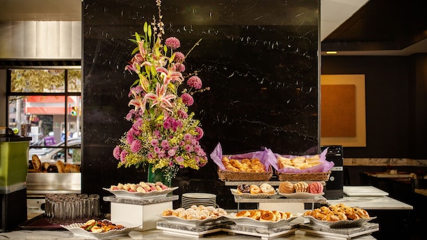 Un bufé con diversos pasteles y un arreglo floral.