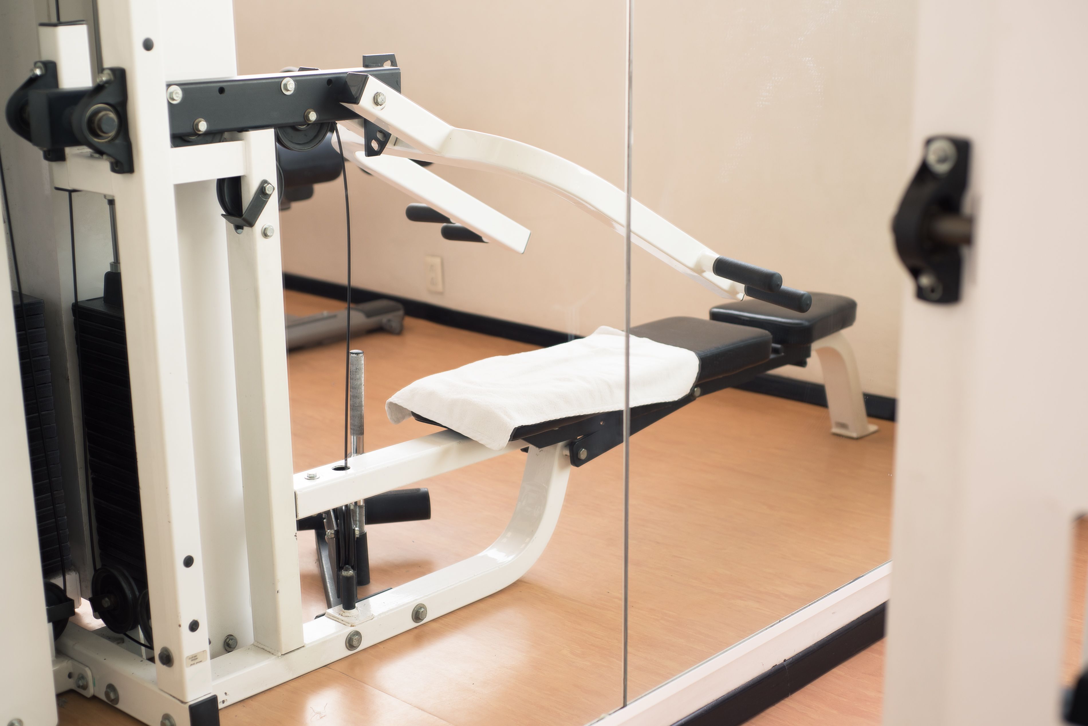 Un gimnasio con equipo de ejercicio, un espejo y suelo de madera.