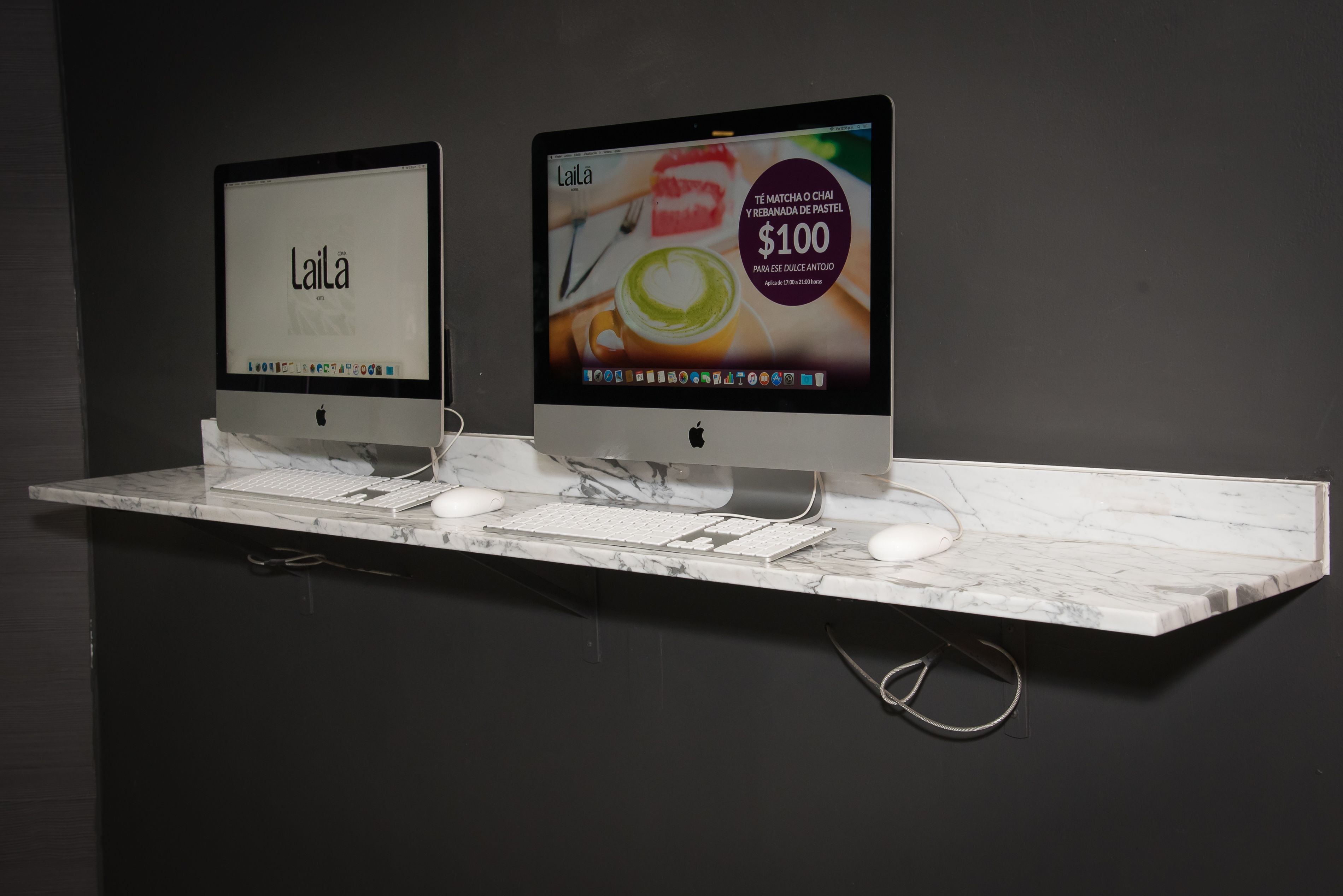 Twee Apple iMac computers op een marmeren aanrecht, met toetsenbord en muis.