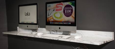 Two Apple iMac computers on a marble countertop with a keyboard and mouse.