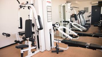 A gym with various exercise machines, a mirrored wall, and a door in the background.