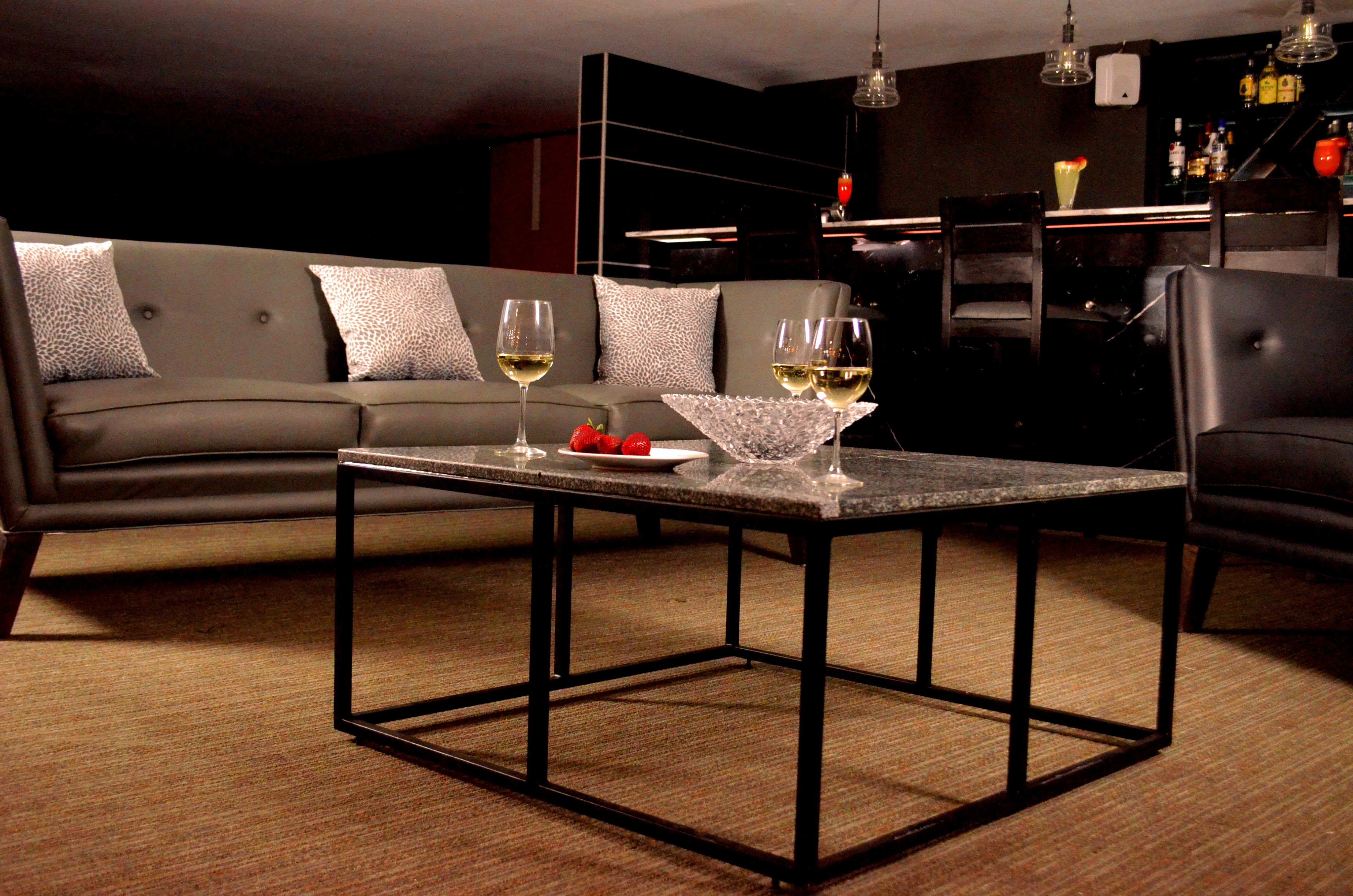 A modern living room with a sofa, a coffee table, and a bar area in the background.