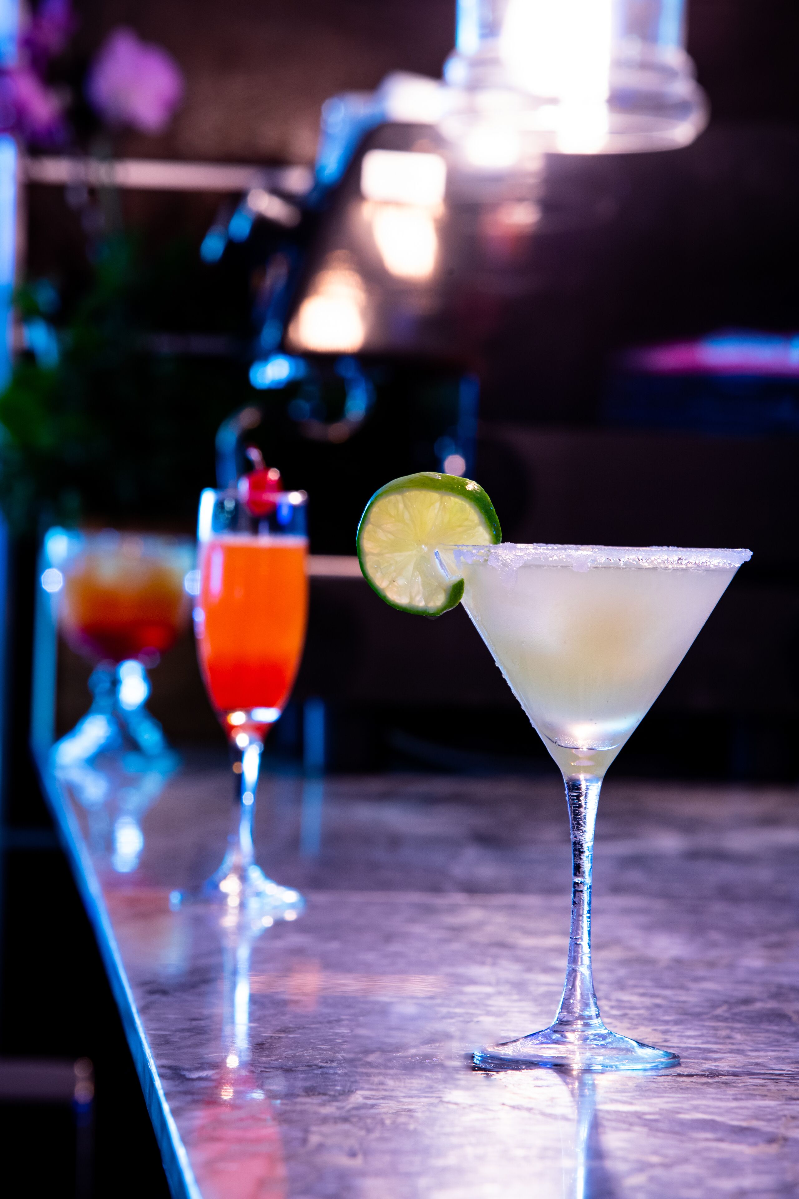 Un bar con tres vasos de martini, uno con una rodaja de lima.
