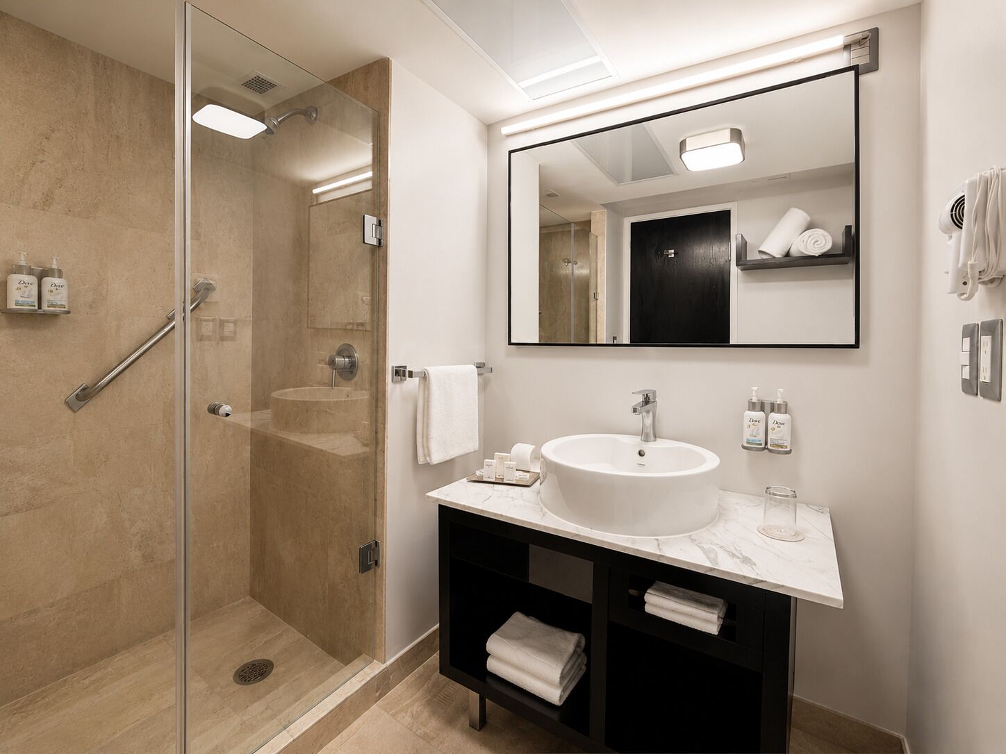 A modern bathroom with a glass-enclosed shower, a large sink, and a mirror above the vanity.