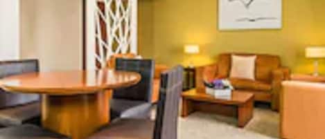 Una habitación de hotel moderna con una mesa de comedor de madera, un sofá y una mesa de centro.