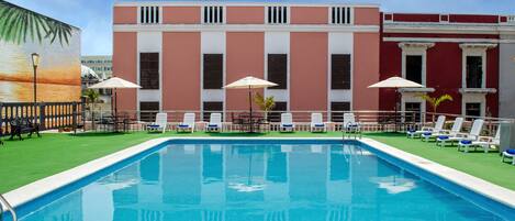 Een buitenzwembad, parasols bij het zwembad en ligstoelen