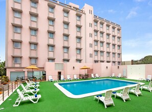Um hotel com área de piscina, incluindo piscina, espreguiçadeiras e guarda-sóis.