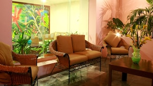 A room with wicker furniture, a glass partition, and a tropical-themed painting. - Veracruz Centro Histórico (Veracruz)