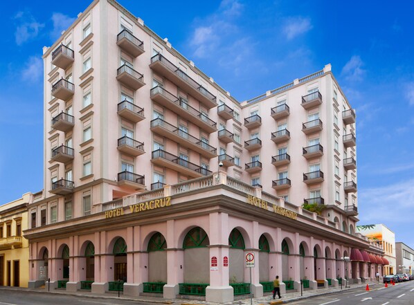 Um edifício rosa com varandas e uma placa com a inscrição "HOTEL VERACRUZ".