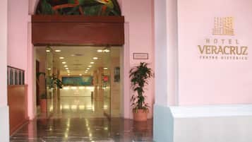 Entrada do Hotel Veracruz Centro Histórico, com porta de vidro, um vaso de planta e uma placa na parede.