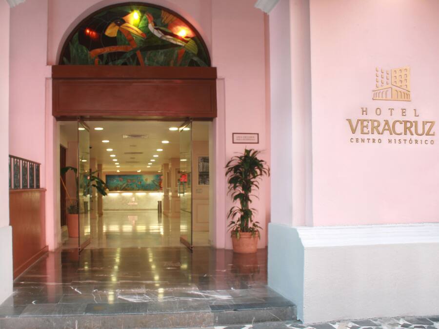 Entrada do Hotel Veracruz Centro Histórico, com porta de vidro, um vaso de planta e uma placa na parede.