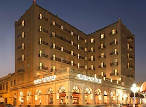 A multi-story hotel with a classic facade, multiple balconies, and a prominent entrance with arched windows.