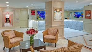 A lobby with wicker furniture, a vase of flowers, and a digital display board. - Veracruz Centro Histórico (Veracruz)