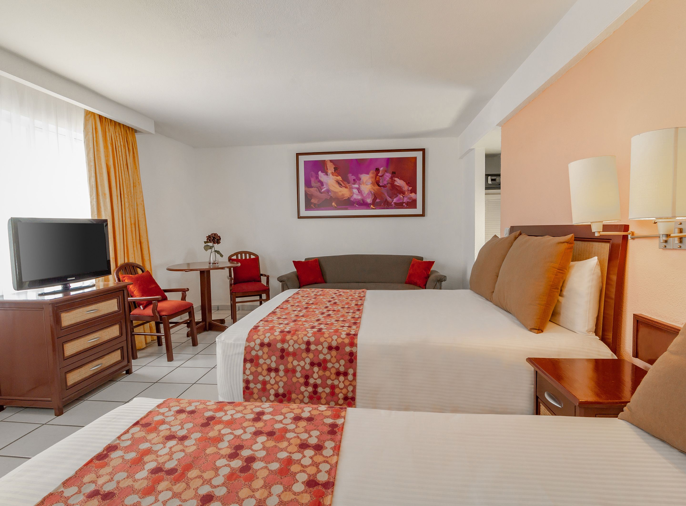 A hotel room with two beds, a TV, a desk, and a chair.