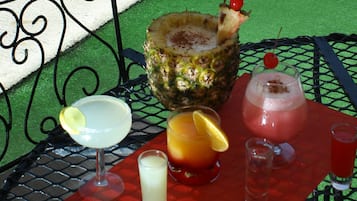 Una mesa con diversas bebidas, incluyendo un cóctel de piña, una bebida roja adornada con cereza y un vaso con rodaja de limón.