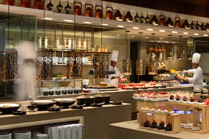 A well-lit buffet area with various dishes and a chef preparing food. - Sule Shangri-La, Yangon (Yangon)