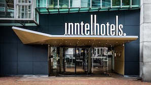 La entrada del Innhotel, con un diseño moderno, presenta un frente de vidrio y una señalización llamativa.