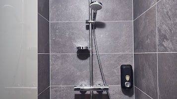 A modern shower with a rain showerhead, handheld showerhead, and a handheld shower attachment.