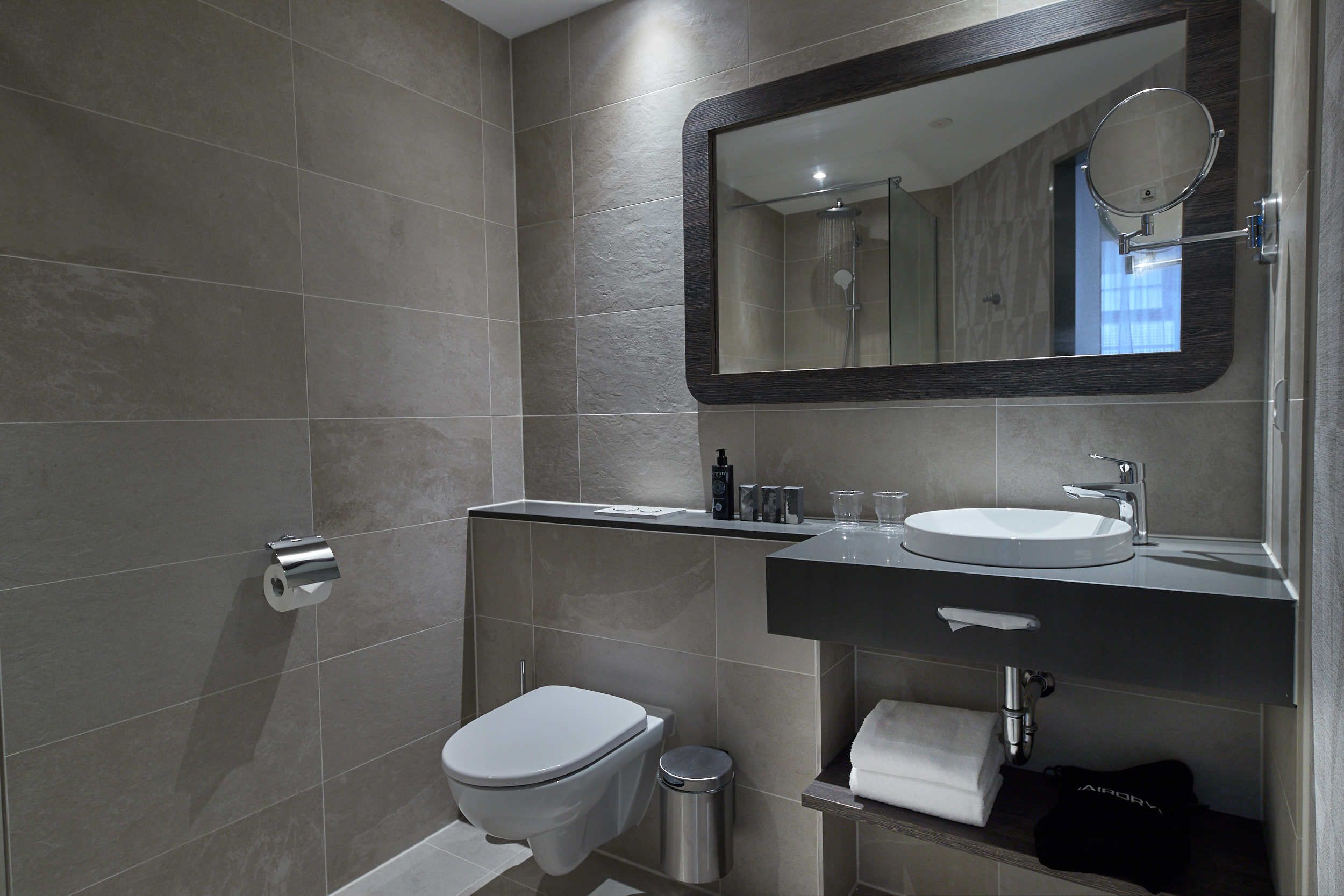 A modern bathroom with a toilet, sink, and mirror.