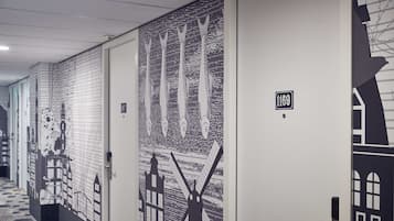 A hallway with doors featuring artistic designs, including windmills and buildings, and a sign with the number 1169.